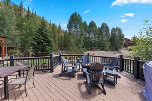 A wooden deck with outdoor seating and a view of a forested area. - Couples retreat backing to the pond in wonderful Breckenridge on shuttle route (Breckenridge)