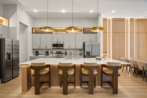 Une cuisine moderne dotée d’un îlot central, d’appareils électroménagers en acier inoxydable et de meubles de rangement en bois.
