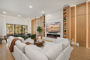 A modern living room with a fireplace, a large flat-screen TV, and a view of the outdoors through large windows. - 15 BD/ 16.5 BA/ Sonoma Resort (4231 SB) (Kissimmee)