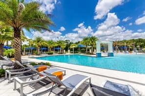 A pool area with lounge chairs and umbrellas, surrounded by palm trees and a clear sky. - 15 BD/ 16.5 BA/ Sonoma (4231 SB) (Kissimmee)