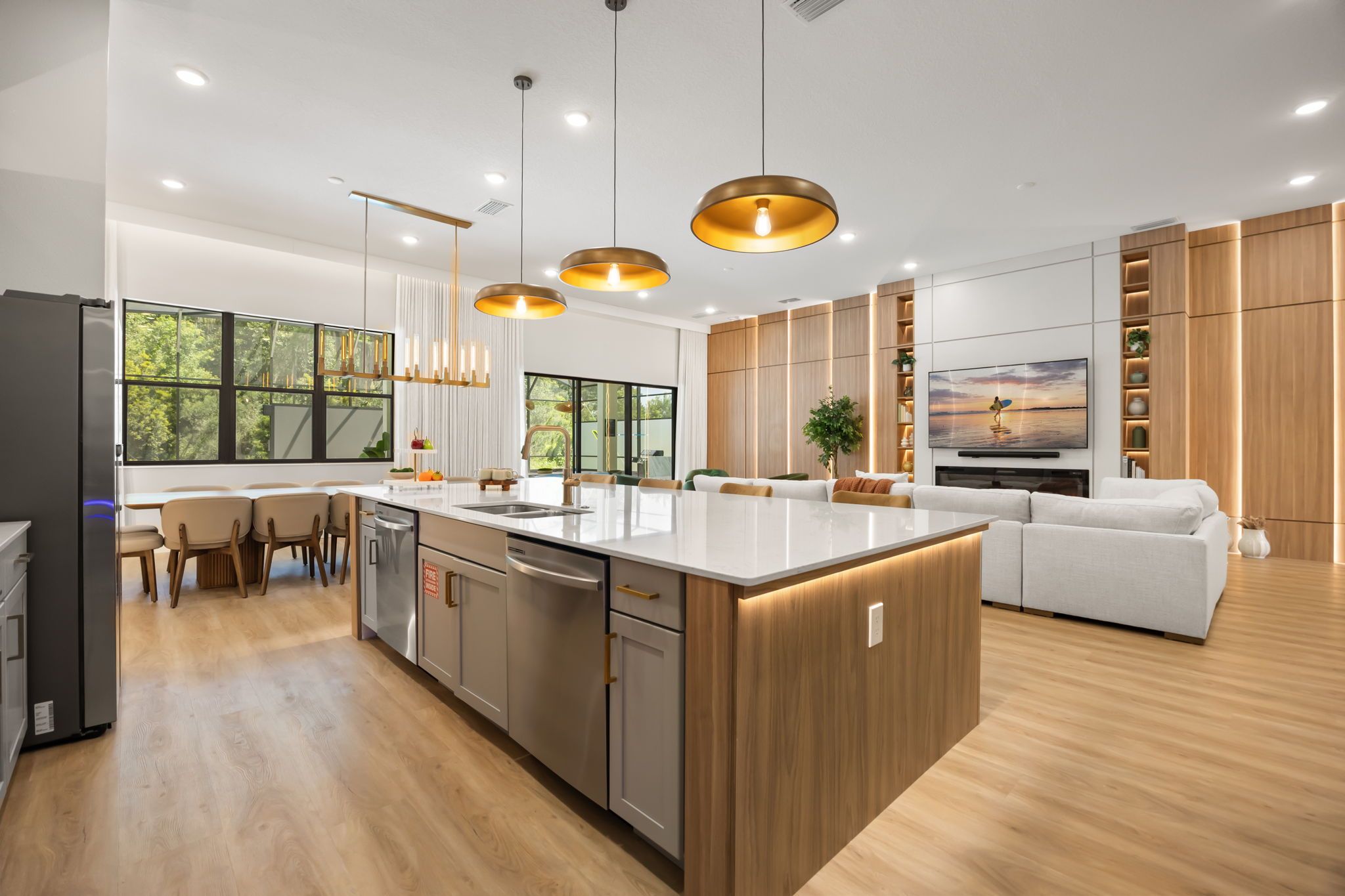 Une cuisine moderne dotée d’un îlot central, de luminaires suspendus et d’un coin repas avec des chaises.