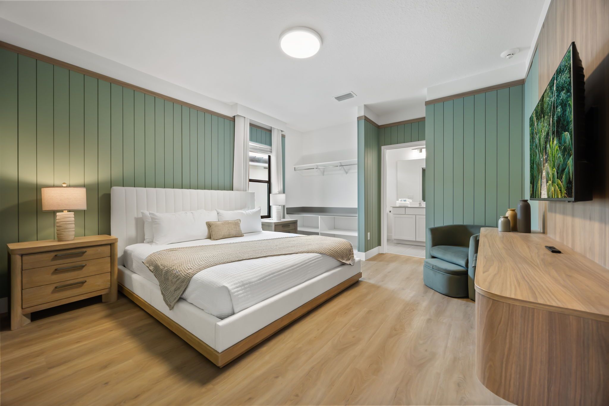 A modern bedroom with a bed, bedside table, and a TV mounted on the wall.