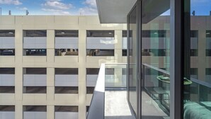 Um edifício com vários andares e varanda de vidro com vista para um estacionamento.