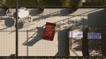 A rooftop terrace with a table and chairs, potted plants, and a railing.