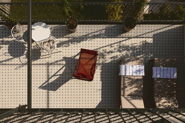 A rooftop terrace with a table and chairs, potted plants, and a railing.