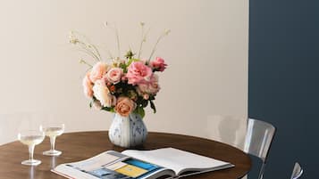 A dining area with a round table, clear chairs, a vase with flowers, and decorative plates on the wall.
