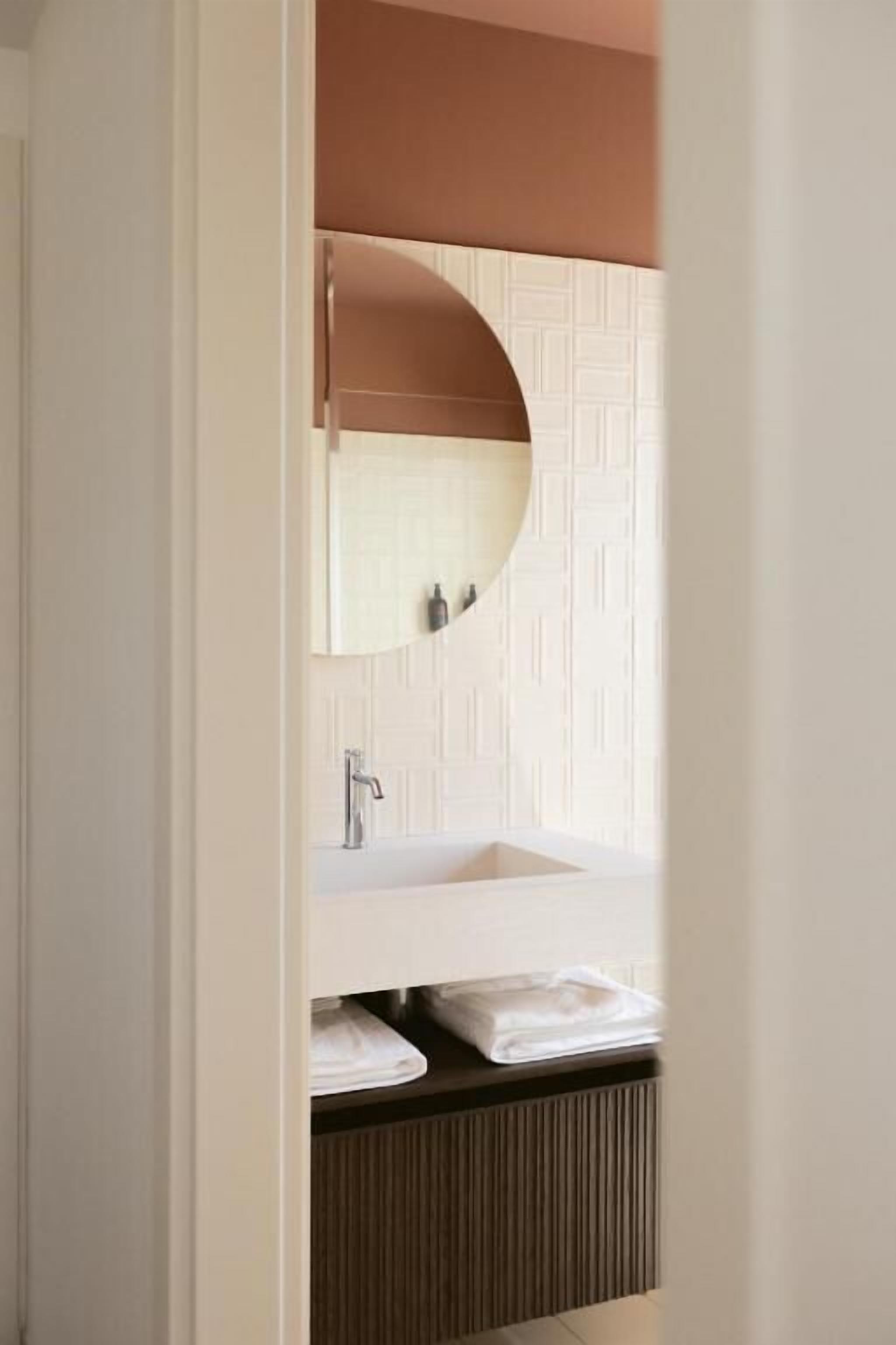 Een badkamer met een wit wastafel, een spiegel en een handdoekhouder.