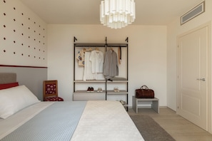 A bedroom with a bed, a wardrobe, a hanging light fixture, and a door.