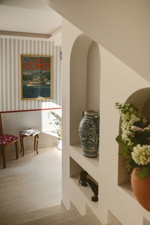 Una habitación con un cuadro en la pared, una silla, una mesa, un florero y una planta.
