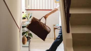 A staircase with a person descending, a brown leather bag, and a small table with a book.
