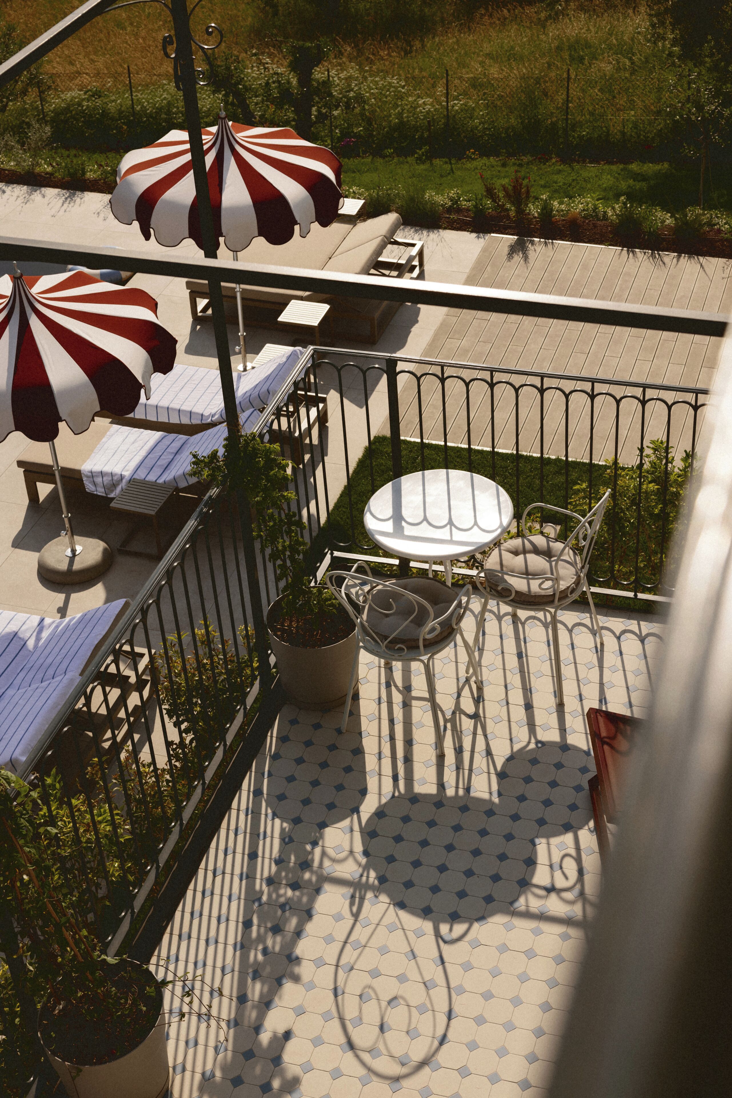 A rooftop terrace with outdoor seating, including tables and chairs, and a potted plant.