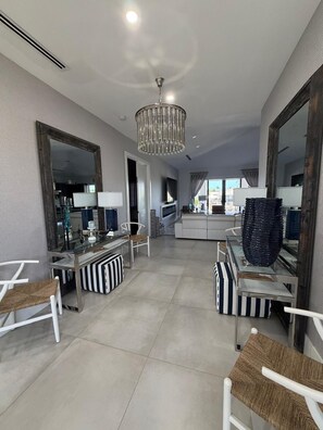 A modern living room with a chandelier, a dining area, and a kitchen in the background. - Modern Port Largo Waterfront  Pool, Dock & Golf Cart (Key Largo)