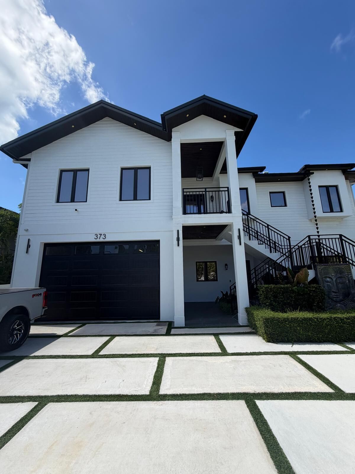 A two-story residential building with a garage, a balcony, and a staircase leading to the upper level.