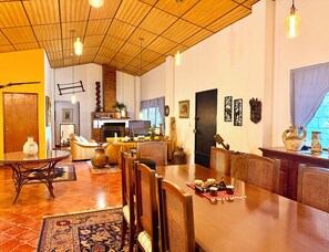 A spacious living area with a wooden ceiling, a fireplace, and a dining table set for four. - Mountain Retreat among Coffee fields & Nature (Los Naranjos)