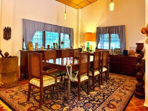 A dining area with a wooden table and chairs, a patterned rug, and a chandelier. - Mountain Retreat among Coffee fields & Nature (Los Naranjos)