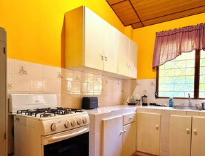A kitchen with a gas stove, oven, and white cabinets. - Mountain Retreat among Coffee fields & Nature (Los Naranjos)