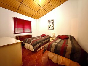 A bedroom with two beds, a desk, a window with blinds, and a wall decoration. - Mountain Retreat among Coffee fields & Nature (Los Naranjos)