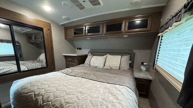Ein Schlafzimmer mit einem Bett, einem Nachttisch, einer Kommode und einem Fenster mit Jalousien.