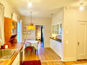 A kitchen with wooden cabinets, a dining table with chairs, and a hanging light fixture. - Charming Historic Tudor (Palestine)
