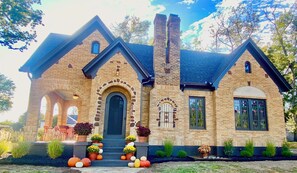 A brick house with a gabled roof, a central entrance with an arch, and a chimney. - Charming Historic Tudor (Palestine)