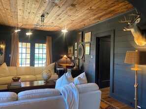 A cozy living room with a wooden ceiling, a mounted deer head, and a globe on the sofa. - Charming Historic Tudor (Palestine)