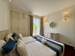 Une chambre d’hôtel avec deux lits, une table de chevet, un miroir et une fenêtre avec des rideaux.