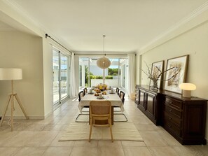 A dining area with a table set for breakfast, a lamp, and a cabinet with artwork. - VILAMOURA SUN & BEACH VILLA WITH POOL by HOMING (Vilamoura)