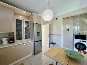 Una cocina moderna con un refrigerador de acero inoxidable, un microondas y una lavadora.