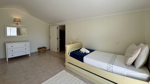 A bedroom with a bed, a dresser, a mirror, and a door leading to another room. - VILAMOURA SUN & BEACH VILLA WITH POOL by HOMING (Vilamoura)