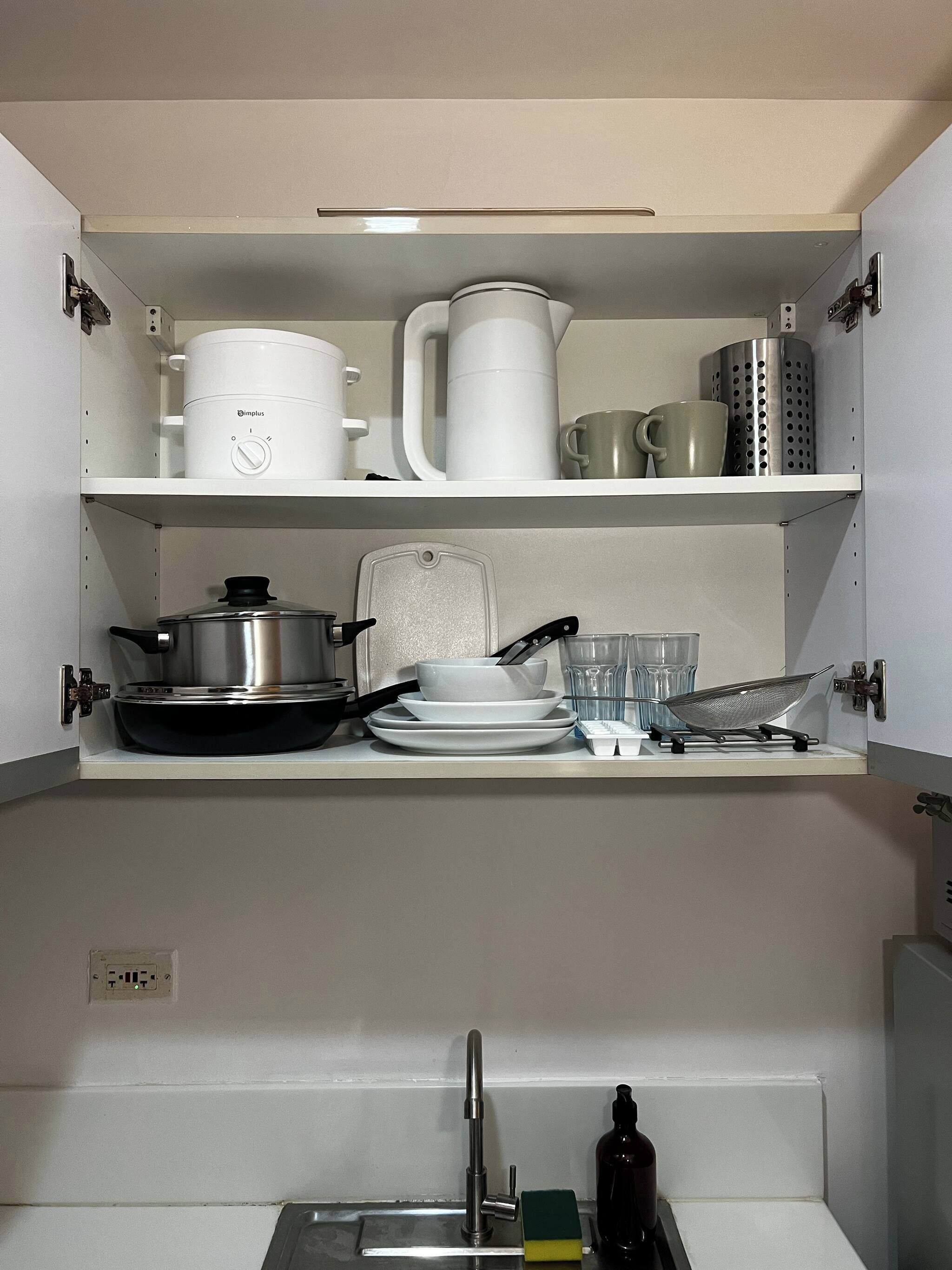 A kitchen with a built-in stove, a sink, and a countertop with various kitchenware.