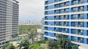 Um edifício alto com várias varandas e uma área de piscina com vegetação.