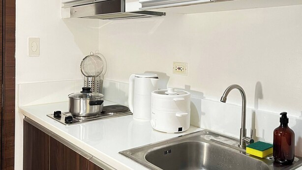 Cozinha moderna com armários brancos, eletrodomésticos de aço inoxidável e uma pia.