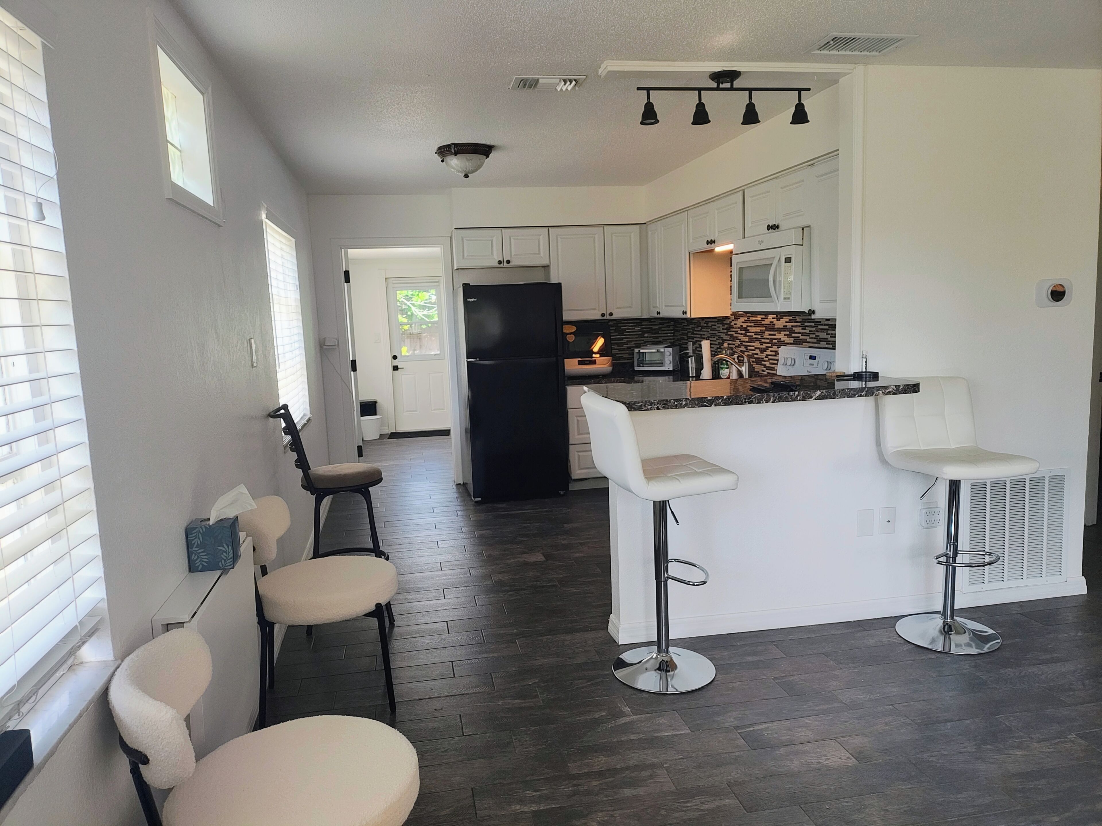 A modern kitchen with a central island, bar stools, and a refrigerator.