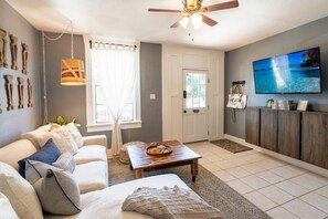 A living room with a sofa, coffee table, and a television on the wall. - Casa Grande | Historic 2BR Bungalow with Private Porch Near Ybor, Armature Works & Downtown Tampa (Tampa)