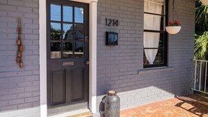 A house with a dark grey brick exterior, a white door with a window, and a mailbox. - Casa Grande | Historic 2BR Bungalow with Private Porch Near Ybor, Armature Works & Downtown Tampa (Tampa)
