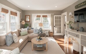 A living room with a beige sofa, a round coffee table, and a white cabinet with a television. - 2-bedroom Private Newport Retreat (Newport)