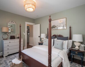 A four-poster bed with a canopy, a bedside table with a lamp, a dresser with a mirror, and a framed picture on the wall. - 2-bedroom Private Newport Retreat (Newport)