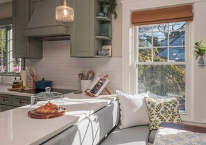A modern kitchen with a built-in island, a hanging light fixture, and a view of the outdoors. - 2-bedroom Private Newport Retreat (Newport)