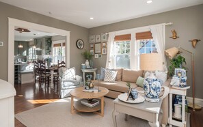 A living room with a sofa, coffee table, and a dining area with chairs and a table. - 2-bedroom Private Newport Retreat (Newport)