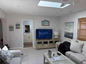 Ett modernt vardagsrum med en platt-TV, en soffa, ett soffbord och en matplats.