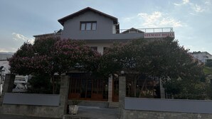 Un hotel de dos pisos con un cartel que dice 'STEMA LU HOTEL' sobre la entrada.