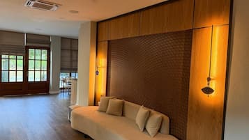 Una sala de estar moderna con un sofá curvo, un panel de pared de madera y vistas al exterior.