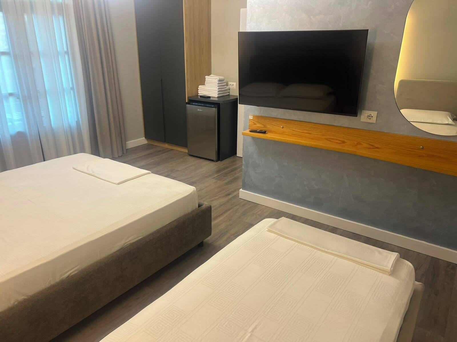 Una camera d'albergo con un letto, una televisione, una scrivania e uno specchio.
