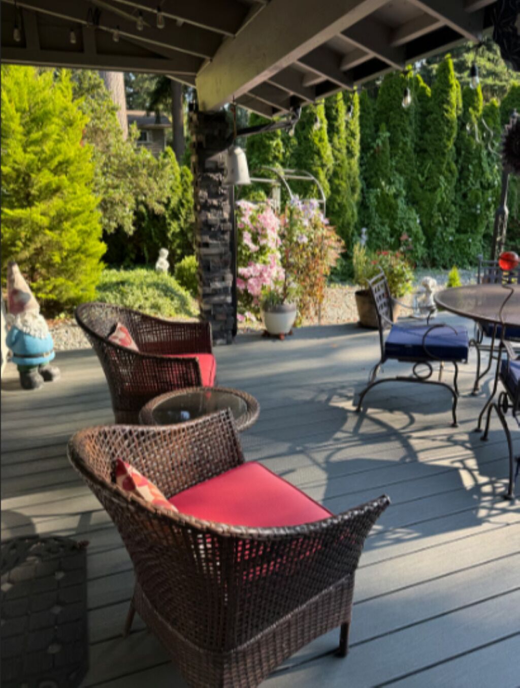 An outdoor patio with wicker furniture, a round table, and potted plants.