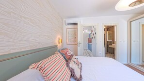 Ein Hotelzimmer mit einem Bett, einer Wandklimaanlage und einer Tür zu einem Badezimmer.