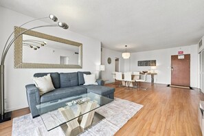 Ein modernes Wohnzimmer mit grauem Sofa, Glastisch und einem großen Spiegel.