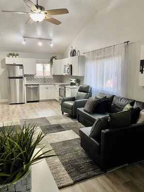 A modern kitchen with white cabinets, stainless appliances, and a ceiling fan. - Sunny Getaway at Sports Village (St. George)