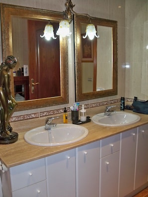 Ein Badezimmer mit zwei Waschbecken, einem großen Spiegel und einer Zierstatue.