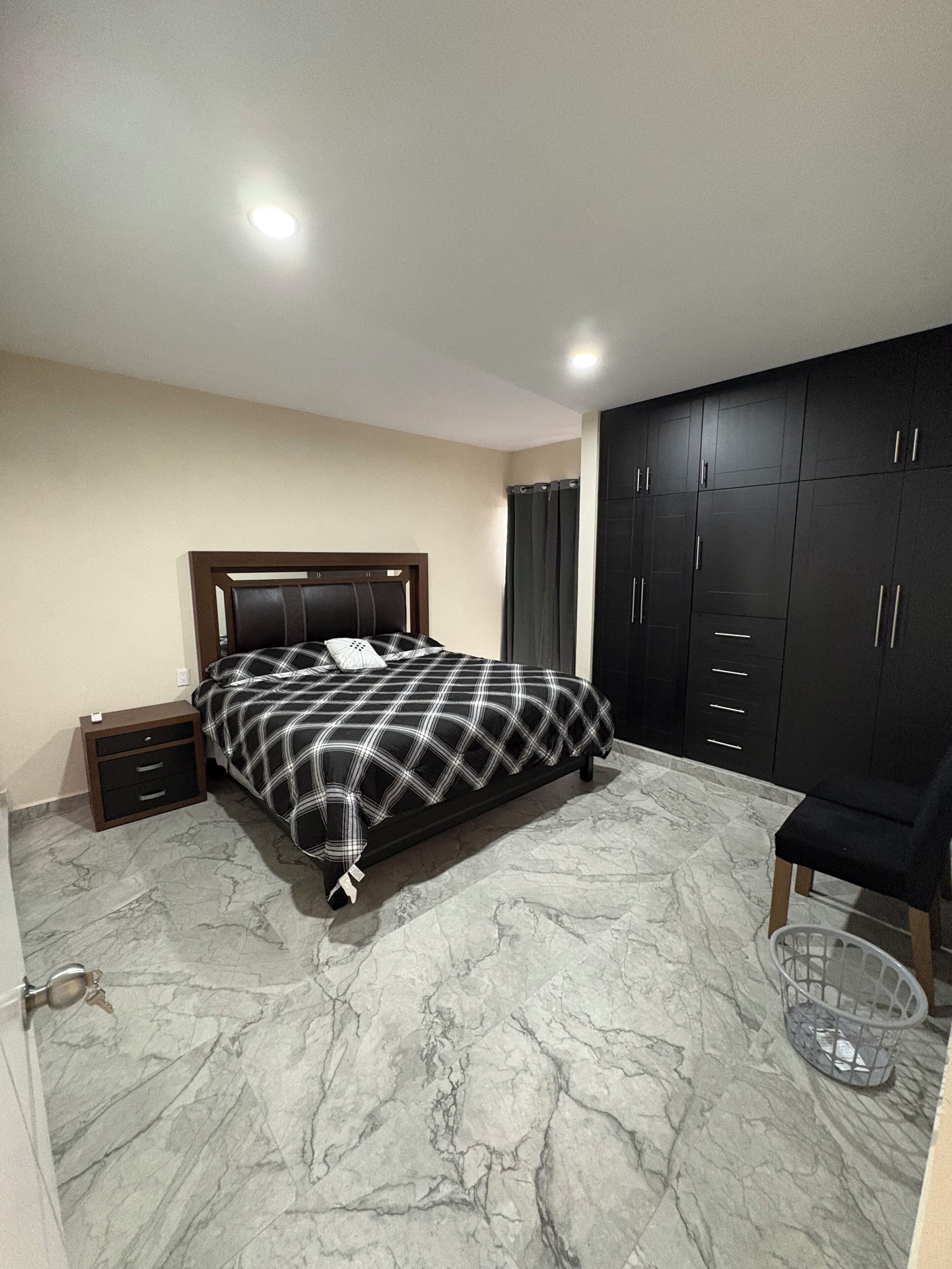 Un dormitorio con cama, mesita de noche, armario y una silla.