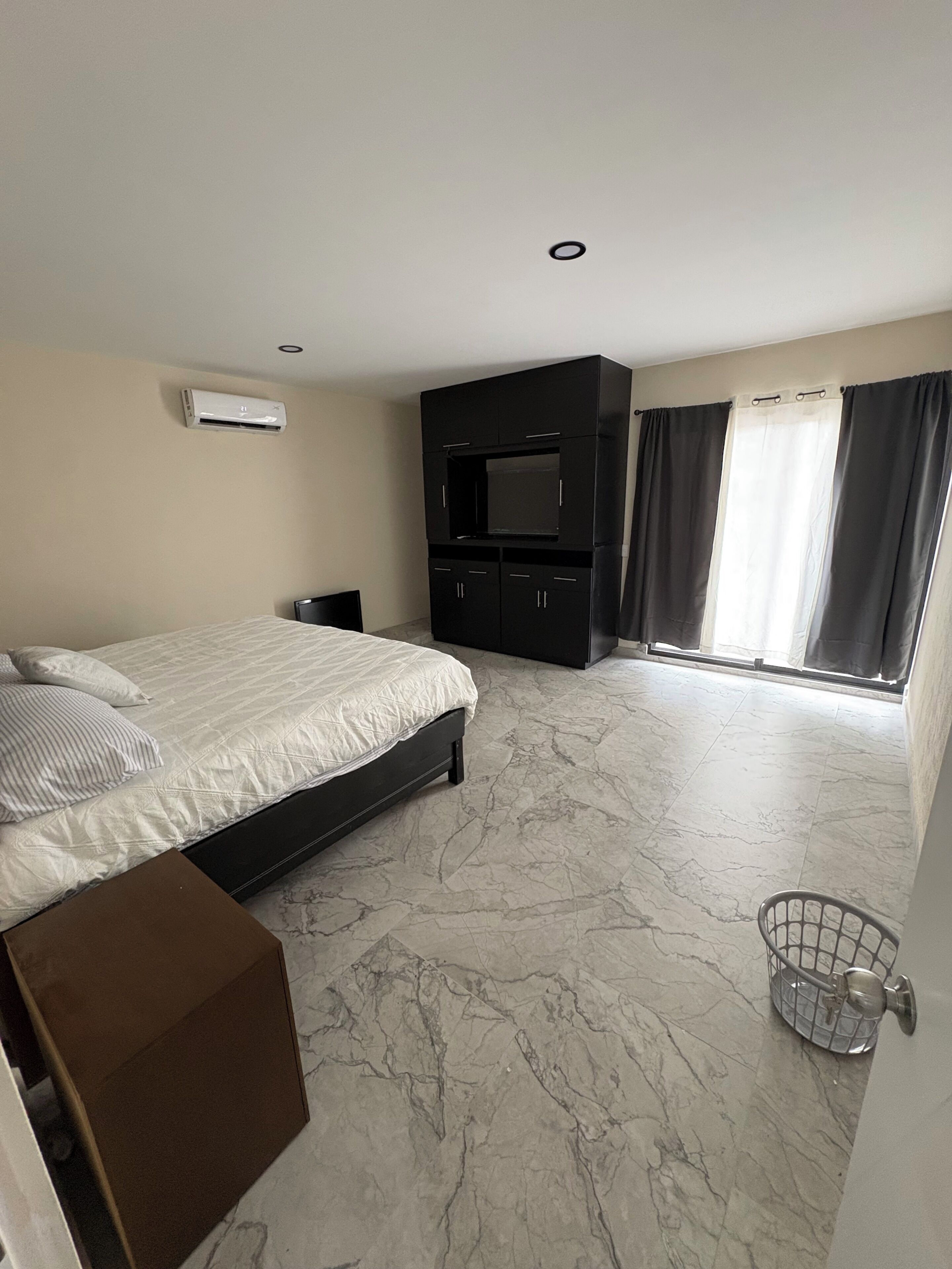 A modern bedroom with a bed, a TV, and a wardrobe.